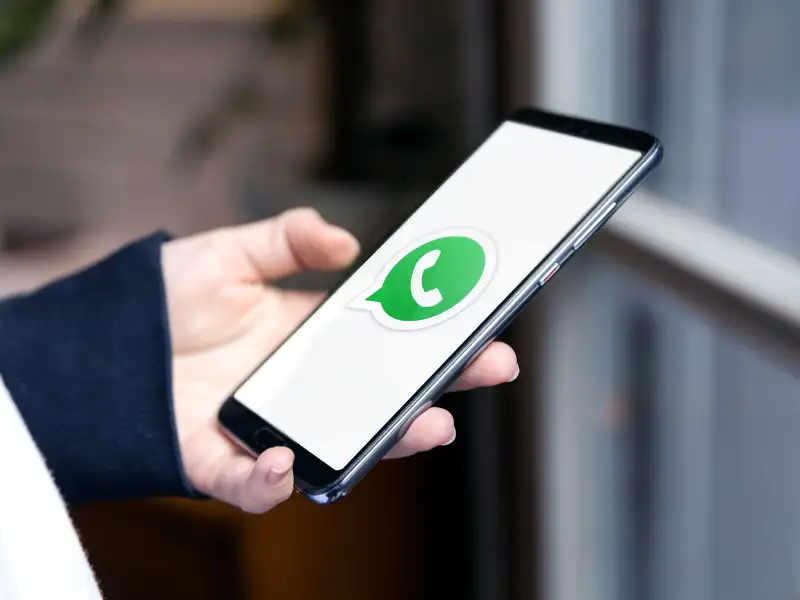 Persona sostiene un smartphone en la mano con la app de WhatsApp abierta.